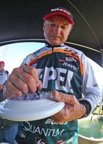 <p>
	Gary Klein autographs a B.A.S.S. Frisbee while waiting to weigh-in.</p>
