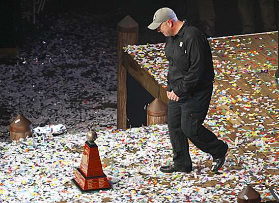 Dave Mercer walks across the confetti-strewn stage to bring the trophy to Lane.
