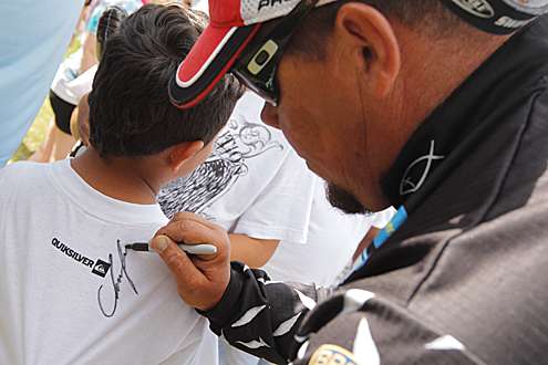 <p>
	2012 Bassmaster Classic champion Chris Lane signs a young fan's t-shirt at the Elite Series Power-Pole Slam Day Four weigh-in.</p>
