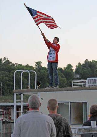 <p>
	A local high school student stands on a nearby house boat, holding the American flag for the National Anthem Sunday.</p>
