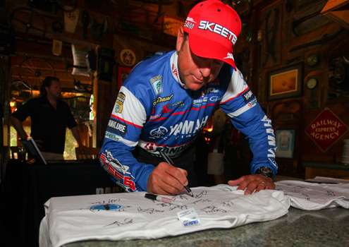 <p>
	Dean Rojas autographs a shirt after checking in. </p>
