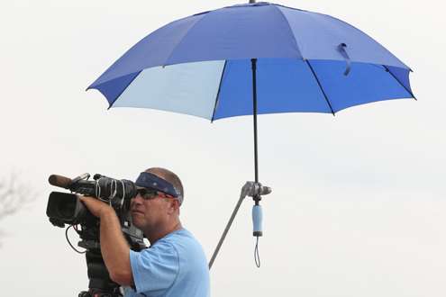 <p>
	A cameraman uses an umbrella to keep the sun off. </p>

