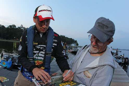 <p>
	Ott DeFoe autographs a magazine cover for a Bassmaster Marshal prior to launch on Day Two of the Toledo Bend Battle.</p>
