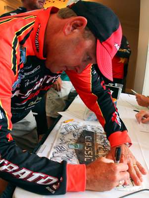 <p>
	Mike McClelland signs B.A.S.S. memorabilia before attending the anglers briefing. </p>
