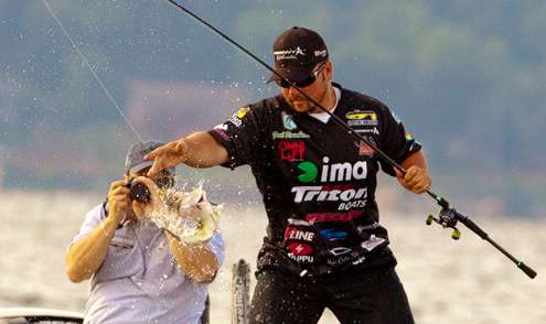 <p>
	Fred Roumbanis jerks a thrashing fish into the boat, while his Day One Marshal aims his camera at the action.</p>
