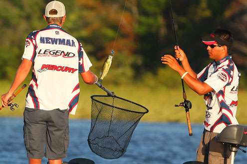 Newman holds the net under the small bass, while Sepeda swings it aboard. 