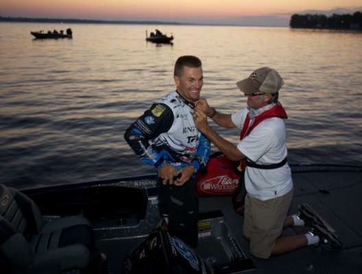 <p>
	Day Three leader Randy Howell gets fitted with a microphone by cameraman Wes Miller, who will be in Howell's boat all day Sunday, recording every catch.</p>
