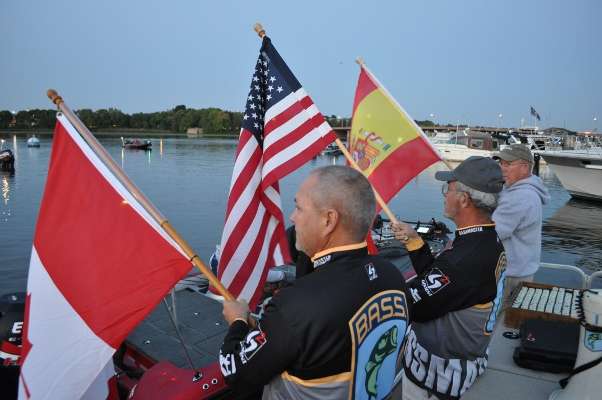B.A.S.S. staffers hold up flags for the countries represented at the divisional â Canada, United States and Spain.
