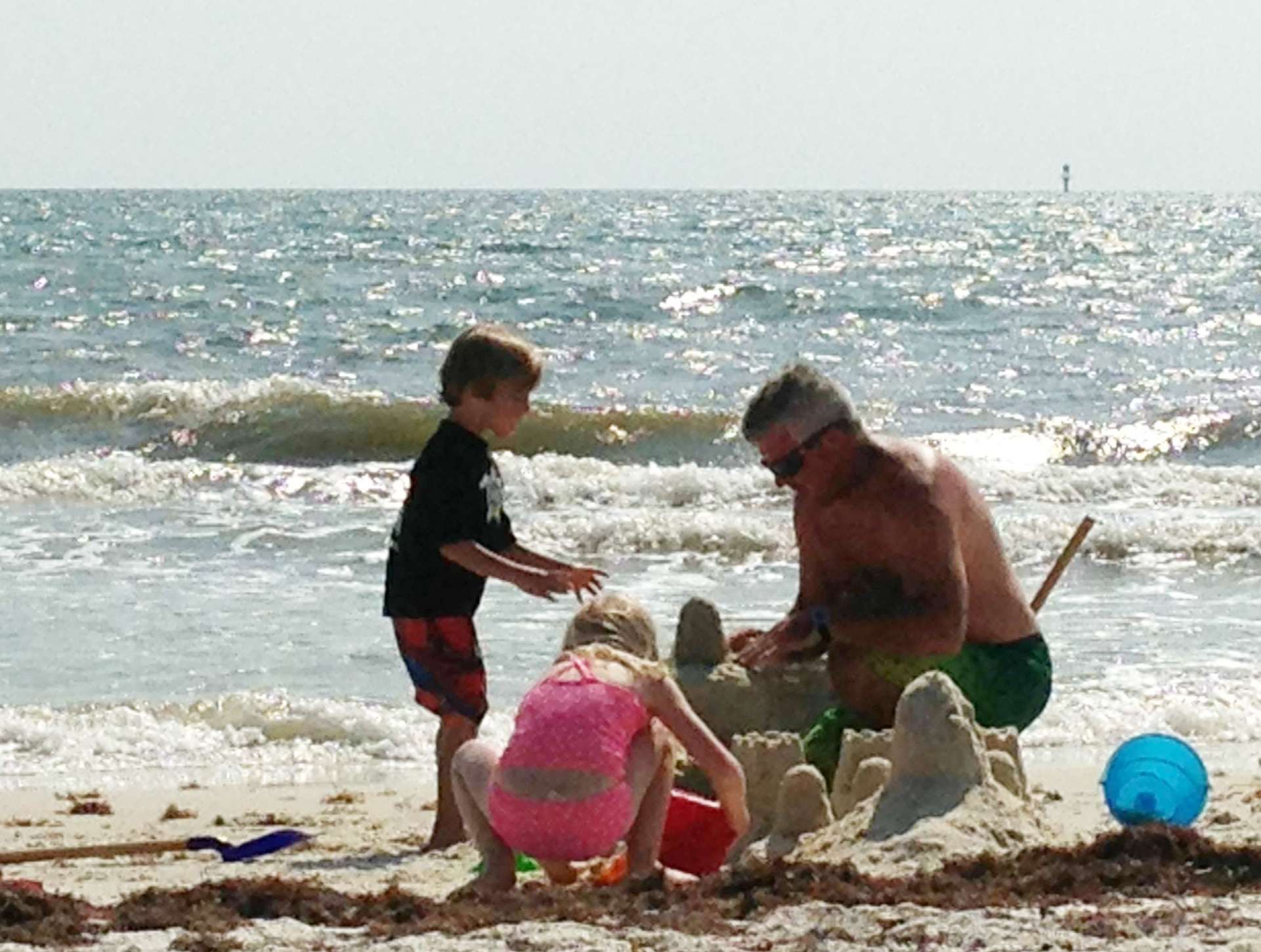 Randall Tharp and family relaxing on the beach, building sandcastles. 