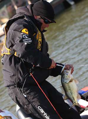 <p>Lee uses his pliers to free the hooks from the bass.</p>
