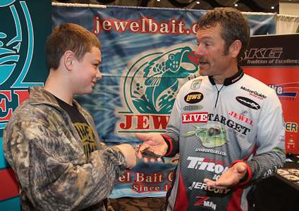 <p>Elite Series angler Stephen Browning shows off a new lure to a young fan in the Jewel Baits booth.</p>
