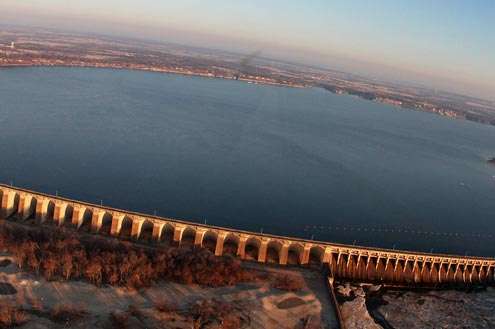 <p>There's a narrow two-lane highway and a walkway on the dam, and the 120 megawatt, 6-unit powerhouse sits at the west end, with 21 spillways on the east end.</p>
