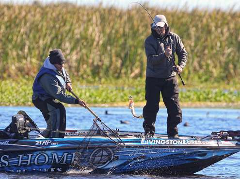 <p>Randy Howell pulls a small keeper bass into the boat.</p>
