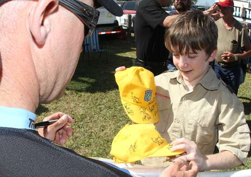 <p>Brent Chapman signs a couple of hats for a Boy Scout.</p>
