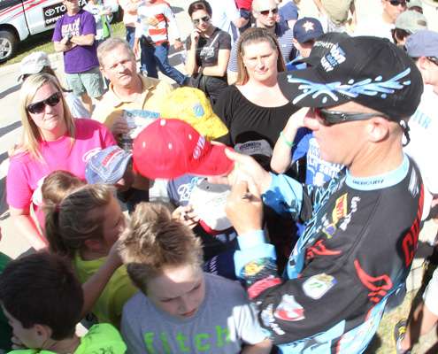 <p>Brent Chapman signs a hat for a group of fans.</p>
