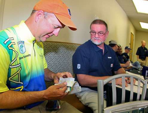 <p>Steve Kennedy sorts through several fishing licenses before producing the license he needs to produce for B.A.S.S. officials to fish on the Sabine River. </p>
