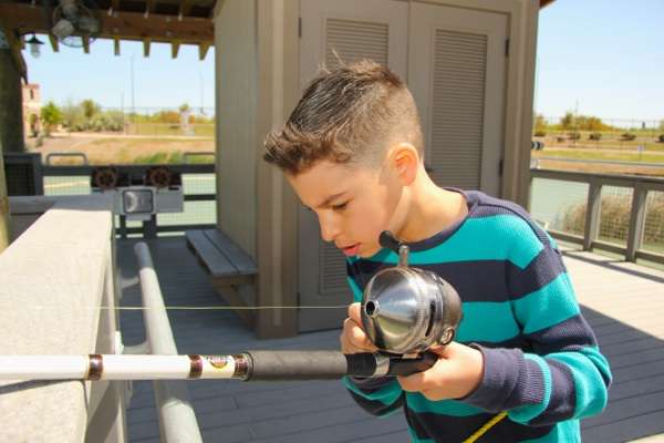 <p>A young angler holds a big Zebco reel with focused concentration awaiting the next bite.</p>
