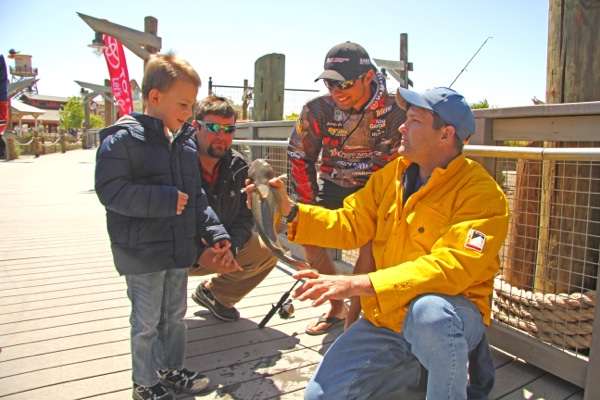 <p>A Morganâs Wonderland volunteer holds a catfish for a young angler, as Palaniuk, and rookie Elite angler Chip Porche look on.</p>
