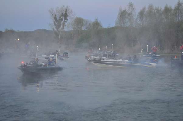 Other boats fall in line amid a light fog.