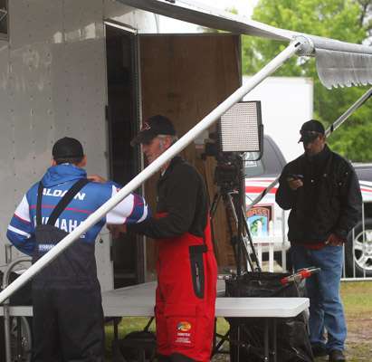 <p>Chris Zaldain gets his mic from Wes Miller prior to an interview with Mark Zona. Zona is in the background checking Bassmaster.com on his phone.</p>
