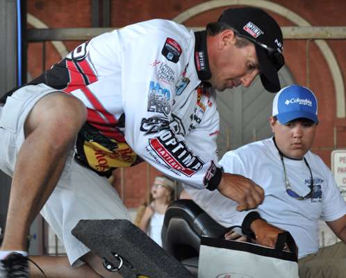 <p>A Marbury High School angler looks on as Edwin Evers transfers his winning bass from livewell to weigh-in bag.</p>
