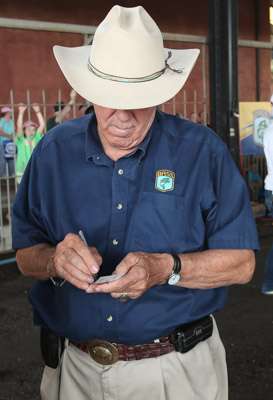 <p>Ray Scott, the founder of B.A.S.S., takes a moment to sign a card for a fan. He always has time for the fans.</p>
