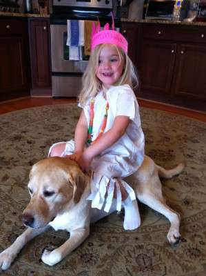 <p>John Crews' yellow lab, Sandy (middle name: Beach!), is the greatest dog to have with small kids, said Crews. "As you can see, my daughter, Myah, is sitting on her with her Pocahontas outfit on and Sandy just loves the attention."</p>
