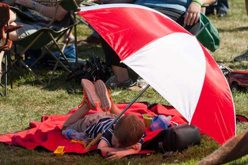 A young fan smartly takes shelter from the heat of the sun.