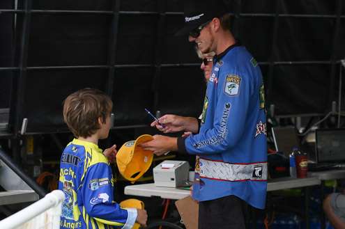 <p>Josh Bertrand takes a moment to sign some hats for the young angler. 18 pounds, 11 ounces after Day One.</p>
