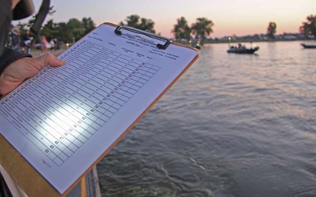 B.A.S.S. officials check names and boat numbers off a list after verifying that every competitorâs livewell is void of bass to begin the new day.