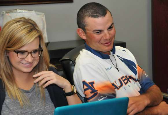 Helen Northcutt, B.A.S.S. editorial assistant, types for Lee as he gives an Auburn battle cry, War Eagle, back to a fan.