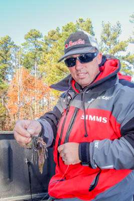 10:45 a.m. Intent on probing shoreline wood cover, Myers ties on a fresh War Eagle jig.