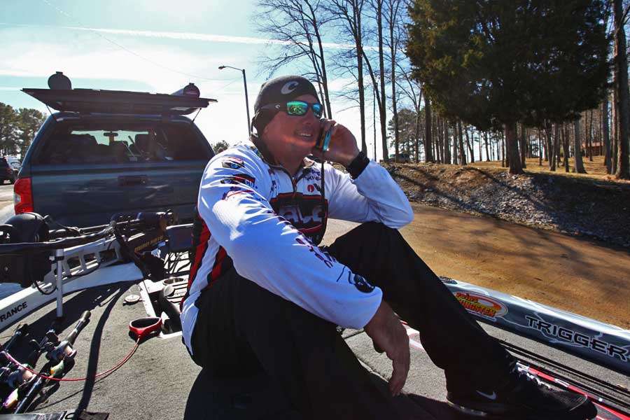 Tharp sits on his deck and talks on the phone while the Evinrude service crew works.