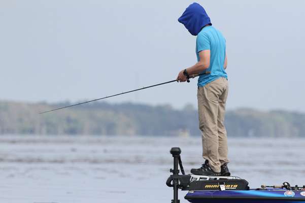 Takahiro Omori fishes on top of his trolling motor, shielding his face with a hoodie.