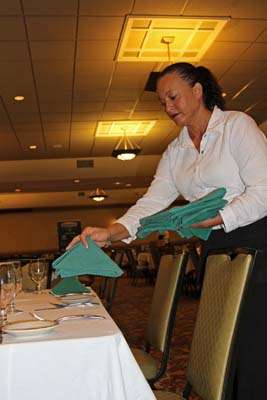 Waitress Pam Ingram prepares place settings prior to the registration dinner.