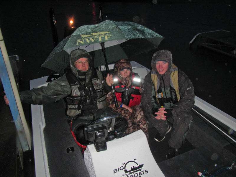 Florida high school anglers Shawn Odor and Trenton Penuel huddle under an umbrella with their coach Fred George prior to the final launch at Lake Eufaula.
