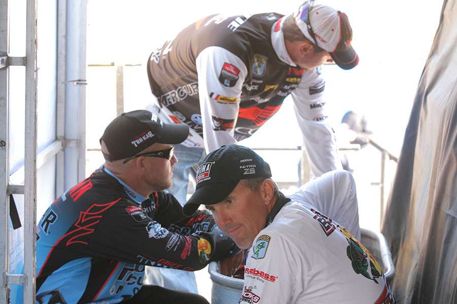 The first three anglers wait behind the stage to weigh in.