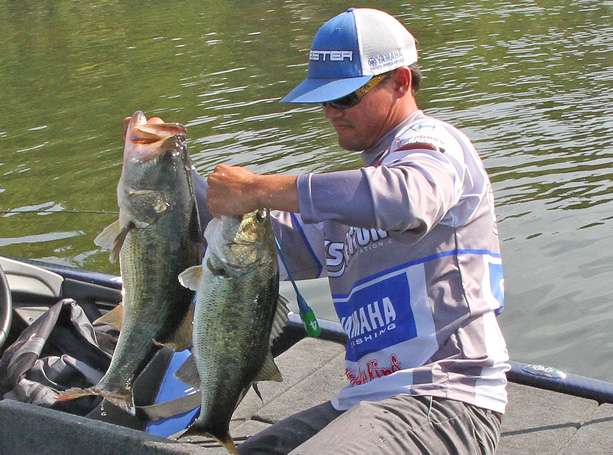 He holds up his two best fish that could collectively weigh around 14 pounds total.