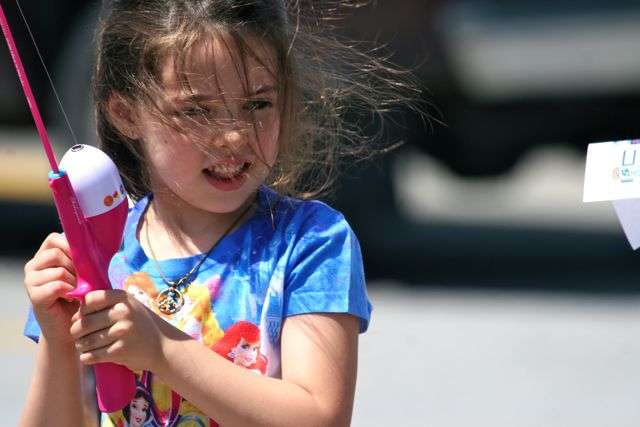 Alivia Avance, 5, of Rogers peers through her wind-blown hair and reels in her line to make another cast. Competition was for ages 7 to 18, but kids of all ages were welcome at the CastingKids event.