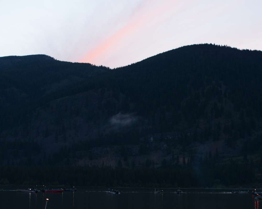 A pink stripe of sunrise forms over the mountain.