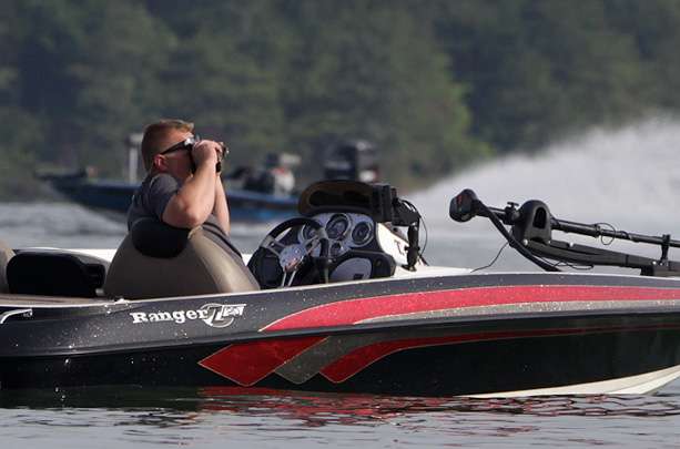  A spectator keeps his distance, watching the Day 2 action with binoculars. 