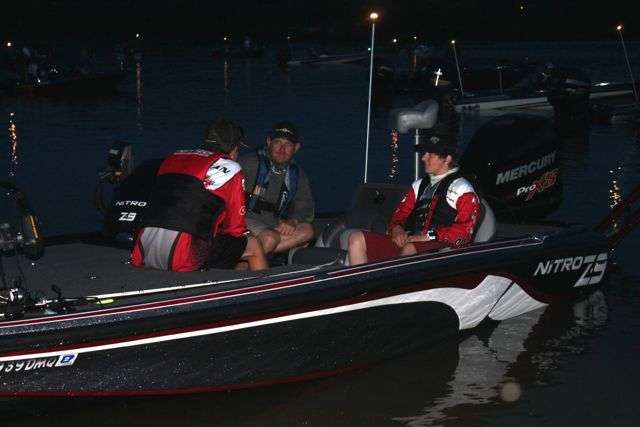 Arkansas B.A.S.S. Nation high school team members Dayten Schureman and Calvin Neff (in red-sleeved jerseys, left to right) talk with their boat driver, Brent Schureman, before launching on their first day of competition in the high school division of the B.A.S.S. Nation Central Divisional on Oklahomaâs Lake Eufaula.