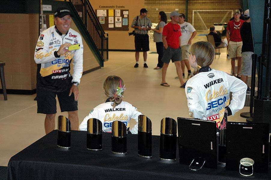 Bassmaster Elite Series pro David Walker takes a photo of his daughters in front of the trophies.  
