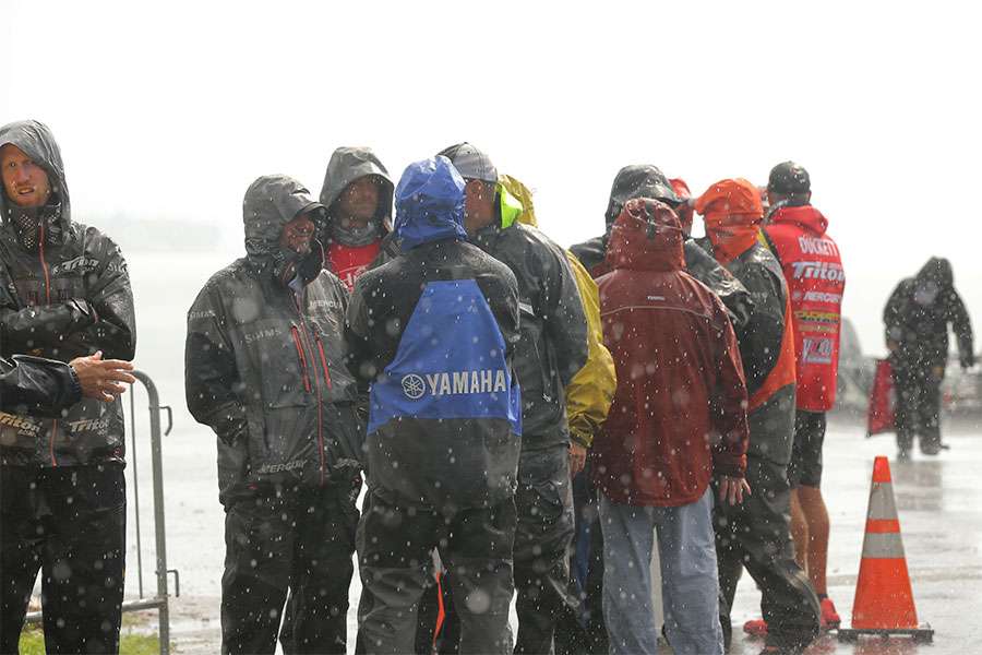 The anglers wait for their weigh-in bags in the rain.