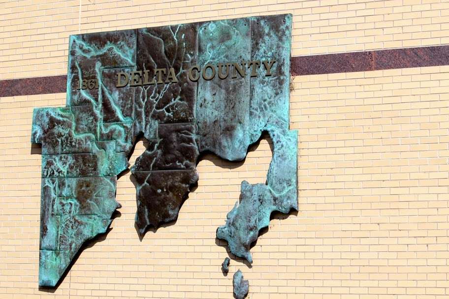 Escanaba is in Delta County Michigan, the metal sculpture up on the wall there is the county, the light brown bricks in the middle of that sculpture is...
