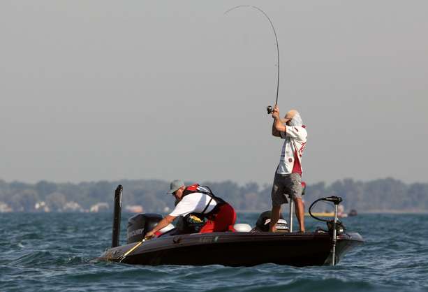 As his co-angler waits with the net, Ramsey makes a hard pull with the rod to bring the fish closer.  