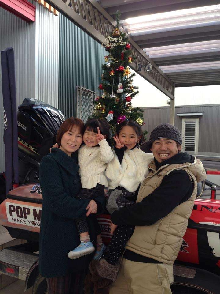 Iyobe and family pose in front of a Christmas tree set up in his boat. 