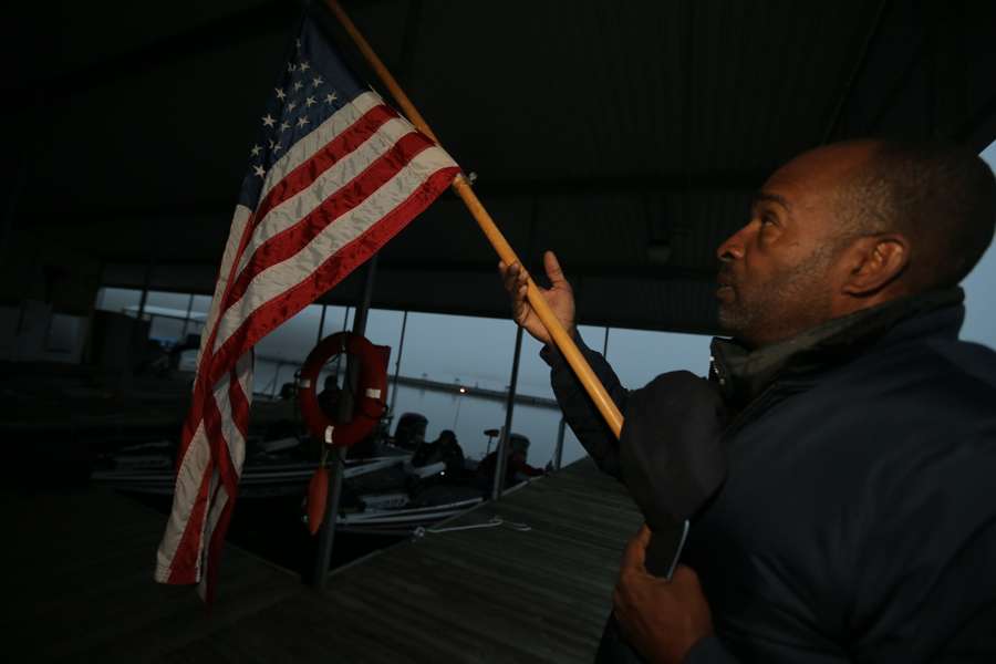 Kent Simmons, who competed during the team championship, holds the flag for the National Anthem.