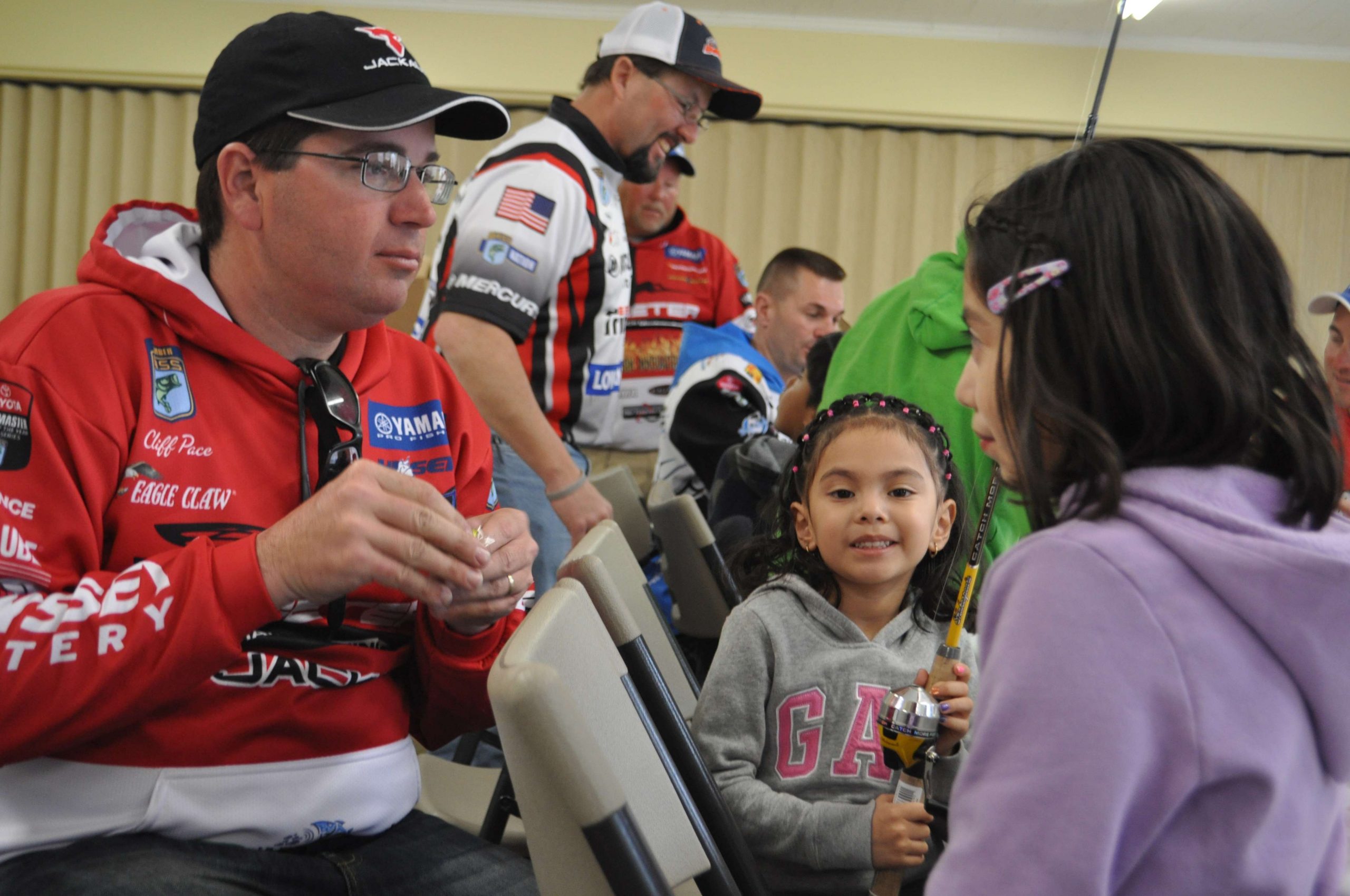 Cliff Pace, 2013 Bassmaster Classic champion, helps two young ladies tie their baits on after they picked out a bright chartreuse lure.