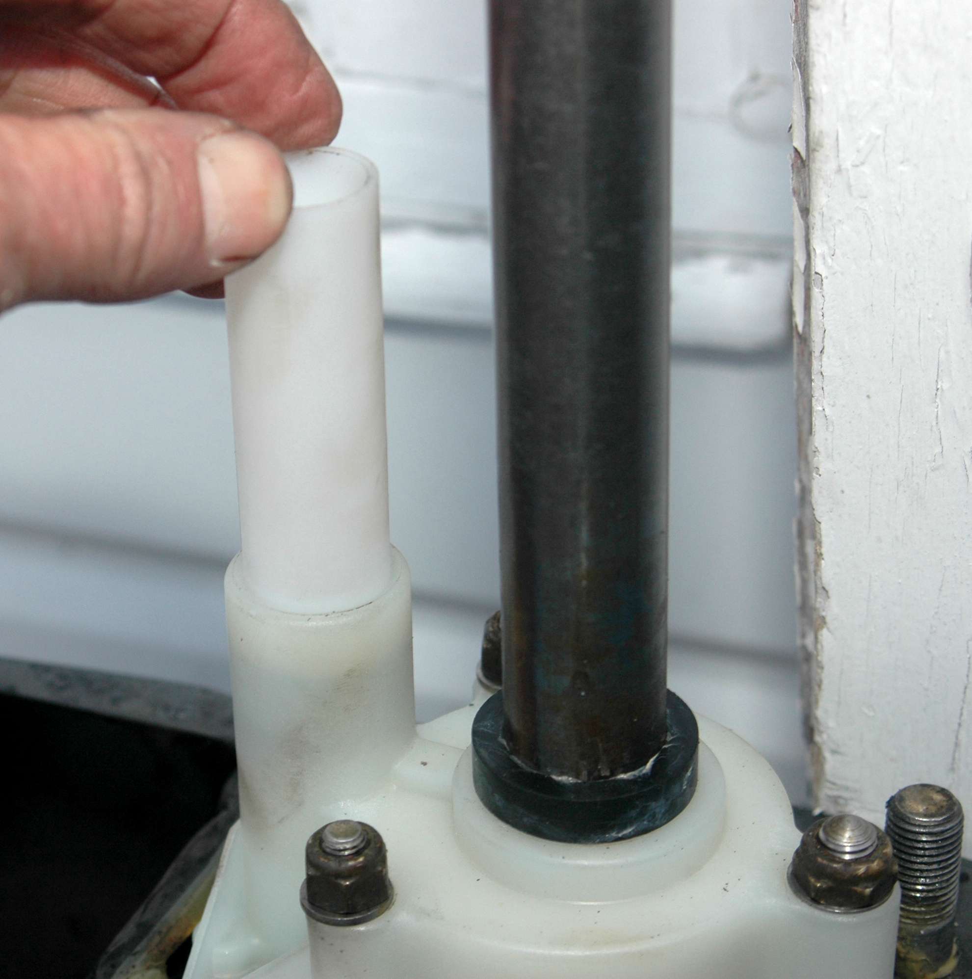 <em>REBUILDING THE WATER PUMP</em>
<br>Secure the washers and nuts. Gradually snug them down crossways to properly seat the gaskets. The white plastic tube is a guide for the water intake in the upper portion of the Mercury XR6. Many other outboards also have a similar guide.